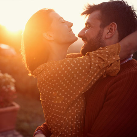 Happy couple embracing with sunset in background